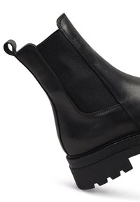 Stivale Chelsea nero con esterno in pelle lucida e pannelli laterali in elastico. Suola in gomma nera spessa e texturizzata per una migliore aderenza.