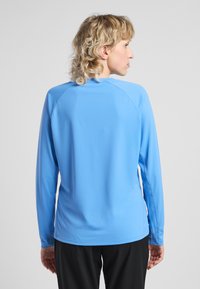 Lange mouw atletisch shirt in lichtblauw, gemaakt van een gladde stof. Kenmerkt zich door raglanmouwen en platte naden. Minimalistisch ontwerp zonder versieringen.