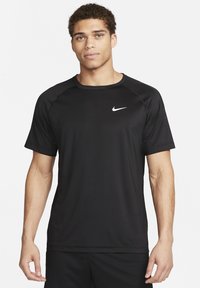 Camiseta deportiva negra de manga corta, elaborada con tela sintética, que cuenta con un pequeño logotipo blanco de Nike en el área del pecho izquierdo.