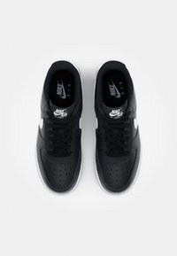 Zapatillas Nike Air Force 1 negras con parte superior de cuero suave, puntera perforada, cordones negros y acentos blancos en el logo y la suela.