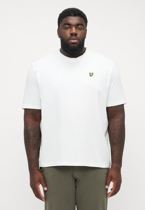 Vit kortärmad T-shirt i mjukt material, med en liten gul logotyp på vänster bröst. Rakt skuren och avslappnad passform.