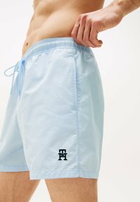 Pantaloni da bagno azzurri realizzati in tessuto leggero. Presentano un elastico in vita, un cordino e un piccolo logo nero sul lato.