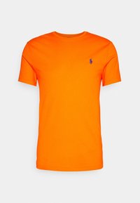 Oranžové bavlněné tričko s kulatým výstřihem a krátkými rukávy. Na levé straně hrudi má malé modré vyšívané logo.