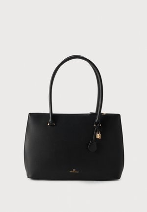 Sac cabas noir texturé avec deux longues anses, des éléments métalliques dorés et une petite étiquette suspendue, sur un fond clair.