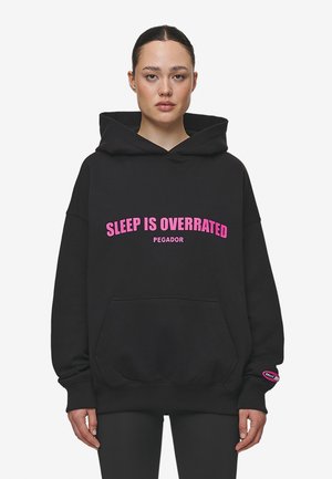 Schwarzer Hoodie aus weichem Baumwollmaterial, mit pinkem Text "SLEEP IS OVERRATED" und "PEGADOR", einer Kängurutasche und gerippten Bündchen.