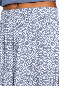 Barriga al aire con una falda hasta la cintura que tiene una banda elástica, con un estampado floral en azul y blanco.