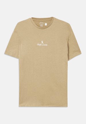 Bežs kokvilnas T-krekls ar īsām piedurknēm, kuram ir balts izšūts logo "Ralph Lauren" un ponija grafika uz krūtīm.