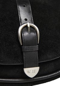 Borsa nera in suede con una fibbia argentata e manico in pelle, con un dettaglio metallico inciso "W. 11" nella parte inferiore. Evidente dettaglio testurizzato.