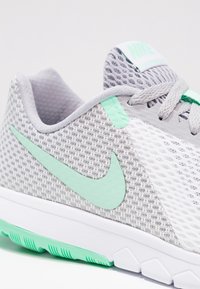 Zapatilla de running de malla gris y blanca con un swoosh de Nike en verde menta, parte superior texturizada y un diseño ligero. Suela de goma con acentos en verde menta.