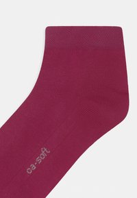 Burgundowe bawełniane skarpetki o gładkiej teksturze i wzmocnionym palcu. Posiadają subtelną metkę z logo w jasnoszarym kolorze blisko kostki.
