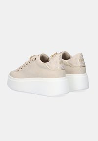 Zapatillas beige con un acabado de ante suave, talón de tela decorado y suela de plataforma blanca. Presentan detalles en dorado y siete ojetes.