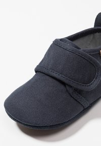 Granatowy materiałowy but z zaokrąglonym noskiem, rzepem i fakturowaną powierzchnią, z miękką podszewką wewnętrzną dla wygody.