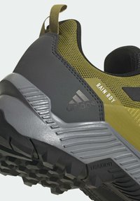 Vihreä ja harmaa vaelluskenkä, jossa on verkkomateriaali yläosa, vahvistettu kantapää, teksturoitu kumipohja ja "RAIN.RDY" yksityiskohta, suunniteltu kostea sää.