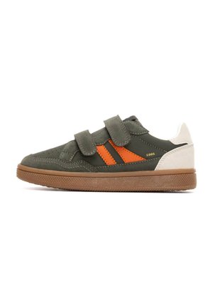 Zapatilla de ante verde con rayas naranjas, correas de velcro, talón blanco y suela de goma marrón. Cuenta con perforaciones en la punta para una mejor transpirabilidad.
