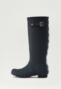 Botas de lluvia negras de goma con un broche lateral, patrón a cuadros azul y blanco en la parte trasera, y suela texturizada para mayor agarre.