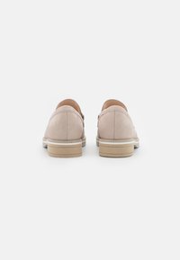 Mocasines de piel rosa claro con un acabado suave, acentos en el tacón y una suela de goma beige. Presenta una costura mínima y una forma redondeada.