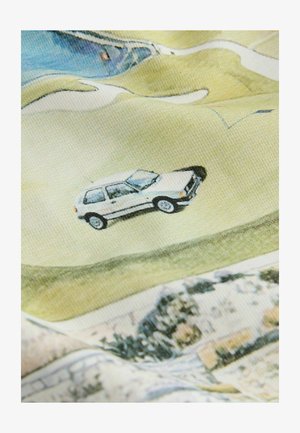 Fehér autó kanyarogva halad egy dombos tájon át, zöld mezőkkel és elszórt fákkal, texturált szövet háttéren.