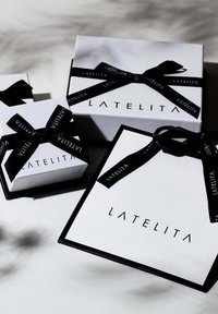Tre vita presentlådor av varierande storlek, prydda med svarta band och "LATELITA"-logotypen i svart, mot en neutral bakgrund.