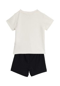 Camiseta de manga corta en tejido acanalado color crema combinada con pantalones cortos azul oscuro, ambos con rayas verticales y un corte holgado.