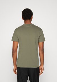 Olive green cotton t-shirt with short sleeves, round neckline, and a straight hem. No patterns or graphics; minimalistic design.