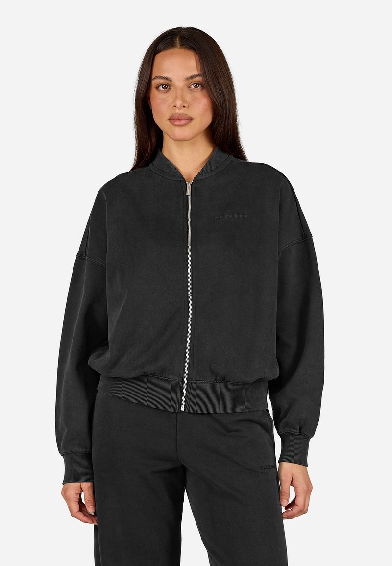 Čierna zipová mikina so voľným strihom, rebrovanými manžetami a pásom. Vyrobená z mäkkého materiálu, s minimálnym brandingom na hrudi.