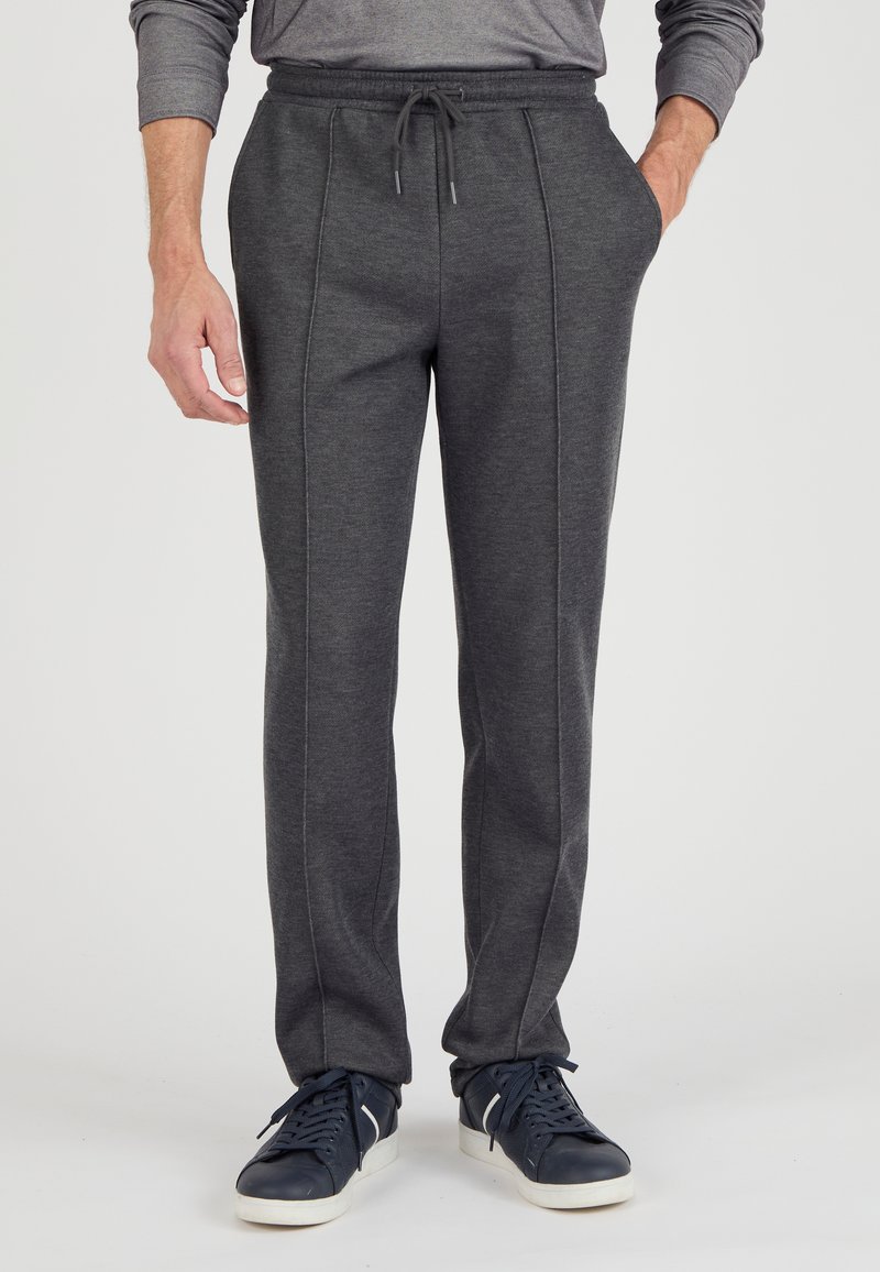 Grijze sweatpants met een trekkoord in de taille, zijzakken en een textuurstof met contrasterende stiksels. Draag ze met donkere sneakers.