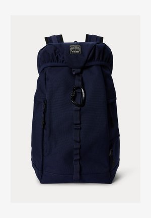 Laivastonsininen reppu, jossa on yläkantti, säädettävät olkahihnat, etumainen lenkki mustalla karabiinilla ja merkitty merkintä keskellä ylhäällä.