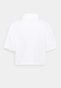 Polo court à manches courtes blanc avec un petit logo Nike dans le haut du dos sous le col.