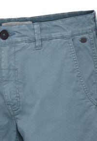 Light blue cotton pants featuring a button closure, front pockets, and a smooth texture. Tag visible near the waistband.