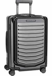 Maleta rígida negra con diseño acanalado, detalles en plata, mango retráctil y cuatro ruedas giratorias para una fácil movilidad.