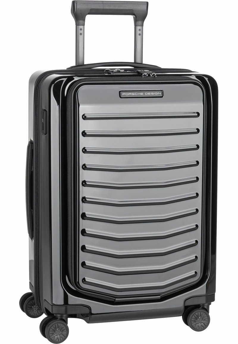 Maleta rígida negra con diseño acanalado, detalles en plata, mango retráctil y cuatro ruedas giratorias para una fácil movilidad.