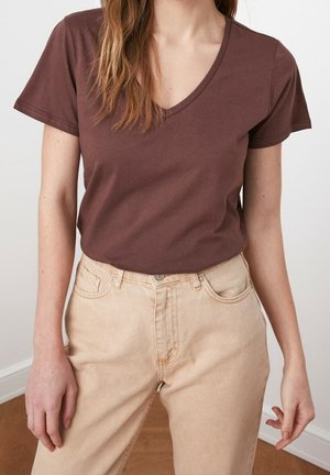 Bruin V-hals T-shirt gemaakt van zachte stof, gecombineerd met lichtbeige high-waisted jeans. Eenvoudig ontwerp met korte mouwen en een ontspannen pasvorm.