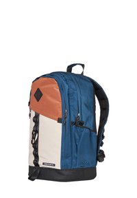 Mochila con paneles azules, naranjas y beige, que presenta cremalleras, un fondo negro texturizado y un asa en la parte superior para llevarla.