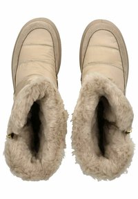 Béžové zimní boty s prošívaným povrchem a měkkým béžovým podšíváním. Kulaté špičky a pevné podrážky obsahují jemné šití a jednoduchý zlatý akcent.