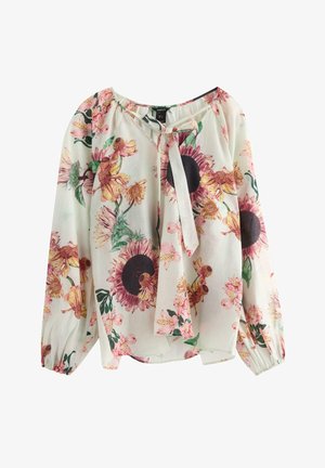 Kukallinen pusero, jossa on kevyt kangas, pitkät hihat, kerätty pääntie ja joukko auringonkukkia sekä vaaleanpunaisia yksityiskohtia vaaleassa taustassa.