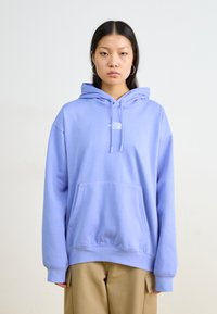 Felpa leggera viola con tasca frontale, cappuccio con cordino e un piccolo logo bianco sul petto. Tessuto morbido e vestibilità comoda.