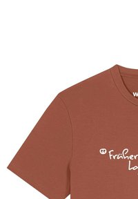 Roestkleurig T-shirt met korte mouwen met gedeeltelijk zichtbare witte bedrukte tekst, waaronder het geciteerde woord "Früher" aan de voorkant.