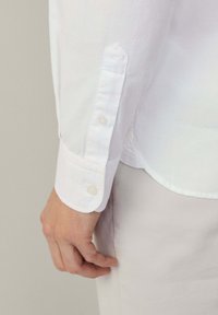 Witte blouse met lange mouwen en knopenmanchetten, gemaakt van glad katoen. Heeft een puntige manchetvorm en een subtiele glans.