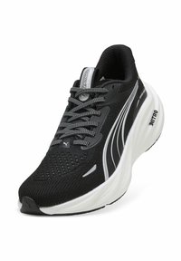 Scarpa sportiva nera con tomaia in maglia strutturata, accenti riflettenti e suola bianca ammortizzata. Presenta lacci grigi e un design elegante.