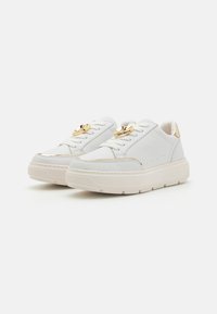White sneakers made of leather with gold accents, including a logo detail on the laces and a chunky sole design. Smooth texture.