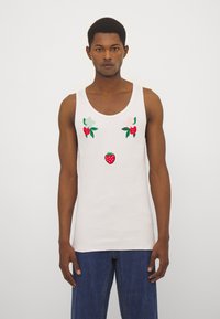 Top blanco sin mangas con bordados florales y de fresas en rojo y verde. Fabricado con tela acanalada y con escote redondo.