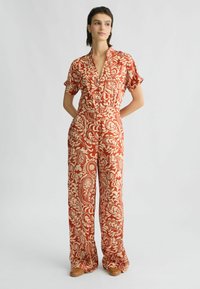 Rode jumpsuit met paisleypatroon, korte mouwen, knopenfront, elastische taille en wijde pijpen. Glad materiaal met een lichte textuur.