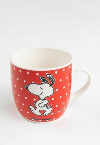 Red ceramic mug featuring a cartoon dog design adorned with white polka dots. Smooth texture with a rounded shape and a handle.