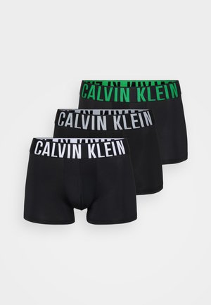 Três pares de boxers pretos com cinturas elásticas: um branco, um cinza e um verde com o logótipo "CALVIN KLEIN" em cores contrastantes.