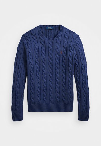 Mornarsko modra pletena jopica z rebraasto vzorcem, okroglo izrezano ovratnikom in rebrastimi manšetami ter robom. Vključuje majhen rdeč logotip na prsih.