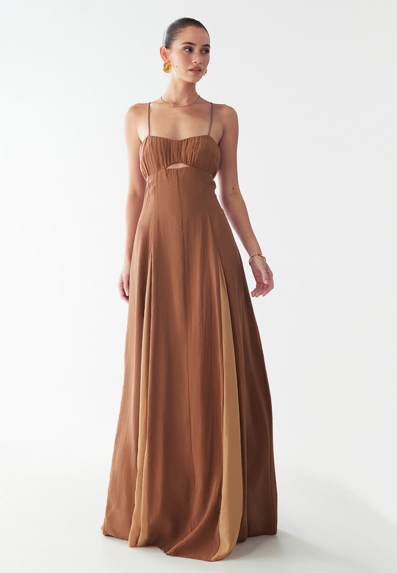 Bruine maxi-jurk met een aansluitend, geraffineerd bovenlijfje en dunne bandjes, met aan de zijkant een paneel in een lichtere bruine tint. Zachte, stroomlijnende textuur.