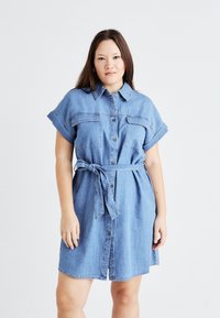 Denim skjortekjole i lys blå, med korte oppbrettede ermer, knappestolpe foran, to brystlommer og belte i midjen for justerbar passform.