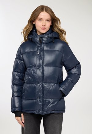 Giacca imbottita blu navy con finitura lucida, forma oversize, cappuccio con coulisse e chiusura con bottoni. Presenta sezioni trapuntate e tasche laterali.