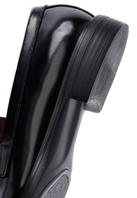 Schwarzer Lederschuh mit glänzendem Finish, runder Zehenform und niedrigem, strukturiertem Gummihoch, der ein schlankes Design zeigt.