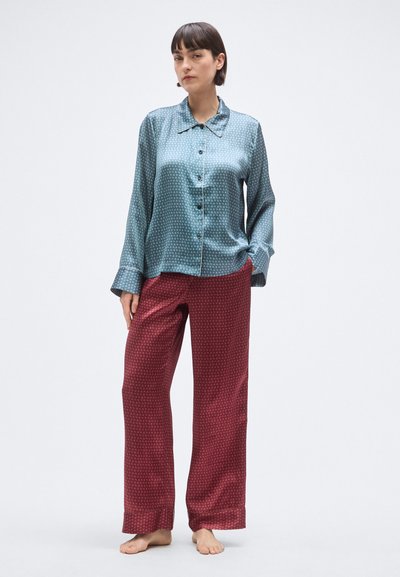 Satynowy komplet piżamowy z turkusową koszulą na guziki z kołnierzykiem i subtelnym wzorem, zestawiony z bordowymi spodniami w wzory. Miękki, lejący się materiał.